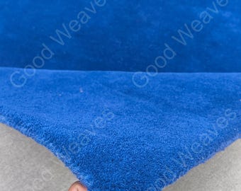 May include: A vibrant royal blue rug with a dense, plush pile texture. The rug is folded to reveal its thick construction and soft surface. The text Good Weaves is overlaid multiple times across the image in a semi-transparent white font.