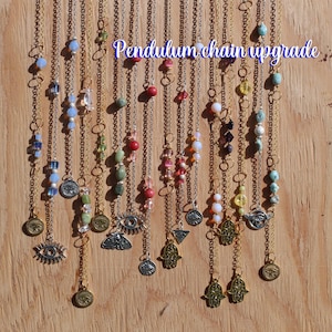 May include: A variety of pendulum chains with different colored beads and charms, including eyes, hamsa hands, and triangles. The chains are displayed on a wooden background with the text "Pendulum chain upgrade".