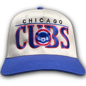 Könnte beinhalten: Baseballkappe mit cremefarbener Krone und blauem Schirm. Die Kappe hat den gestickten Text "CHICAGO CUBS" in Blau und Rot, mit einem kreisförmigen Logo eines blauen Bären.
