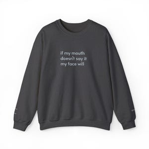 Puede incluir: Sudadera gris oscuro con el texto blanco "if my mouth doesn't say it my face will". La parte superior de cuello redondo de manga larga tiene un diseño simple y minimalista, adecuado para el uso diario.
