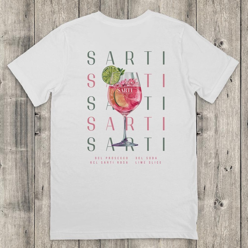 May include: White t-shirt with a cocktail illustration in a stemmed glass. The design includes the word "SARTI" in a vertical pattern, and the ingredients: prosecco, Sarti Rosa, soda, and lime slice.