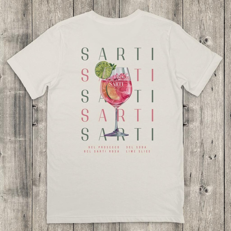 May include: Cream-coloured t-shirt with a cocktail graphic. The design features the word "SARTI" repeated vertically, a cocktail illustration with a lime slice, and the ingredients: Prosecco, Sarti Rosa, Soda, and Lime.