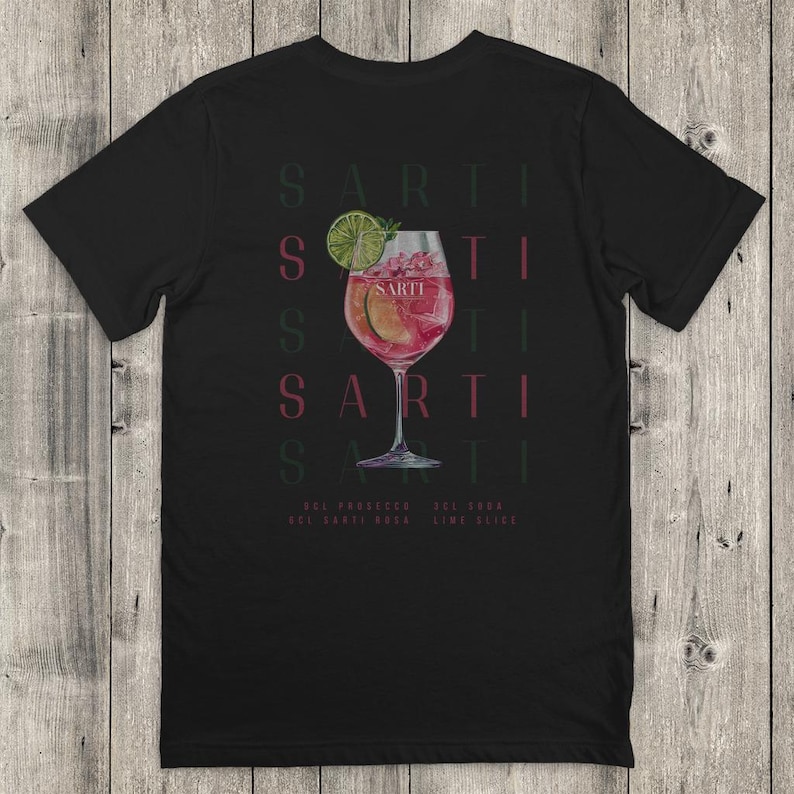 May include: Black t-shirt with a cocktail design. The design includes a stemmed glass with a pink drink, lime garnish, and the word "SARTI" repeated vertically. Ingredients are listed at the bottom.
