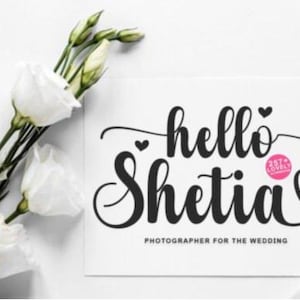 Puede incluir: Una tarjeta blanca con las palabras "hello Shetia" en escritura negra, con un s&iacute;mbolo de coraz&oacute;n. La tarjeta tambi&eacute;n dice "Fot&oacute;grafo para la boda". Rosas blancas y anillos de boda dorados tambi&eacute;n est&aacute;n en la imagen.