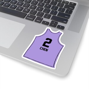May include: A sticker in the shape of a basketball jersey, in a light purple color, with the number "2" and the name "CHEN" printed in black. The sticker is on a laptop.