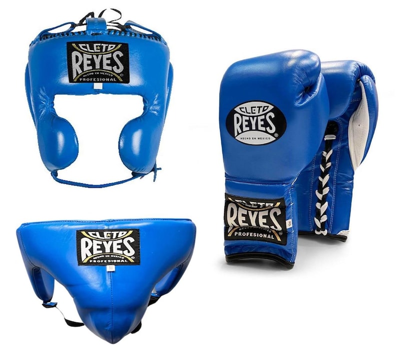 May include: A set of blue boxing equipment, including a headgear, a pair of gloves, and a groin protector. Each item features the "REYES" logo in black and gold. The gloves have white laces.