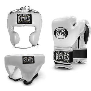 May include: White boxing headgear, gloves, and groin protector set. The headgear has a face opening and adjustable straps. The gloves have a wrist strap with the brand name "CLET0 REYES" in black and gold. The groin protector is white with a black and gold logo.