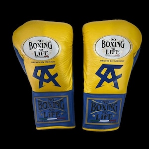 K&ouml;nnte beinhalten: Ein Paar gelb-blaue Boxhandschuhe. Auf den Handschuhen steht "NO BOXING NO LIFE" und "HECHO EN MEXICO". Ein blaues Logo ist ebenfalls auf den Handschuhen zu sehen.