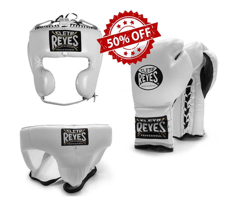 May include: White boxing headgear, gloves, and groin protector set. The headgear and groin protector have the "CLET0 REYES" logo. The gloves are white with black accents and lace-up closures. A red "50% OFF" sticker is in the background.