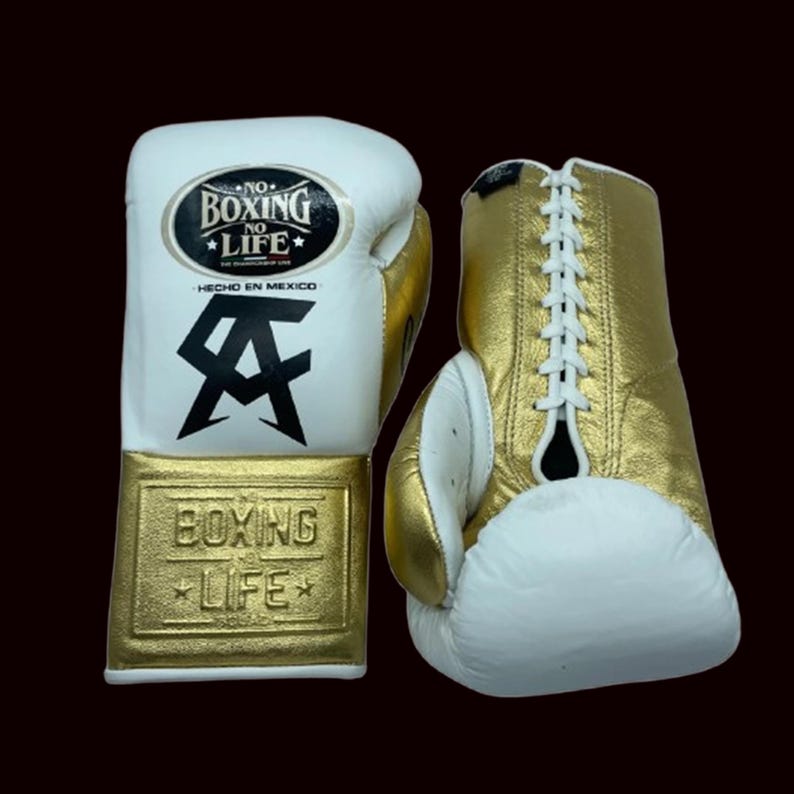 K&ouml;nnte beinhalten: Paar wei&szlig;e und goldene Boxhandschuhe. Die Handschuhe tragen den Text "NO BOXING NO LIFE" und "BOXING LIFE". Die Handschuhe haben wei&szlig;e Schn&uuml;rsenkel und werden in Mexiko hergestellt.