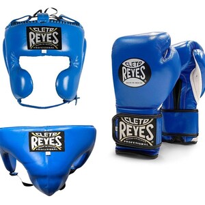May include: A set of blue boxing equipment, including a head guard, a pair of gloves, and a groin protector. Each item features the "CLET0 REYES" logo in white and gold. The gloves have white accents on the inside.