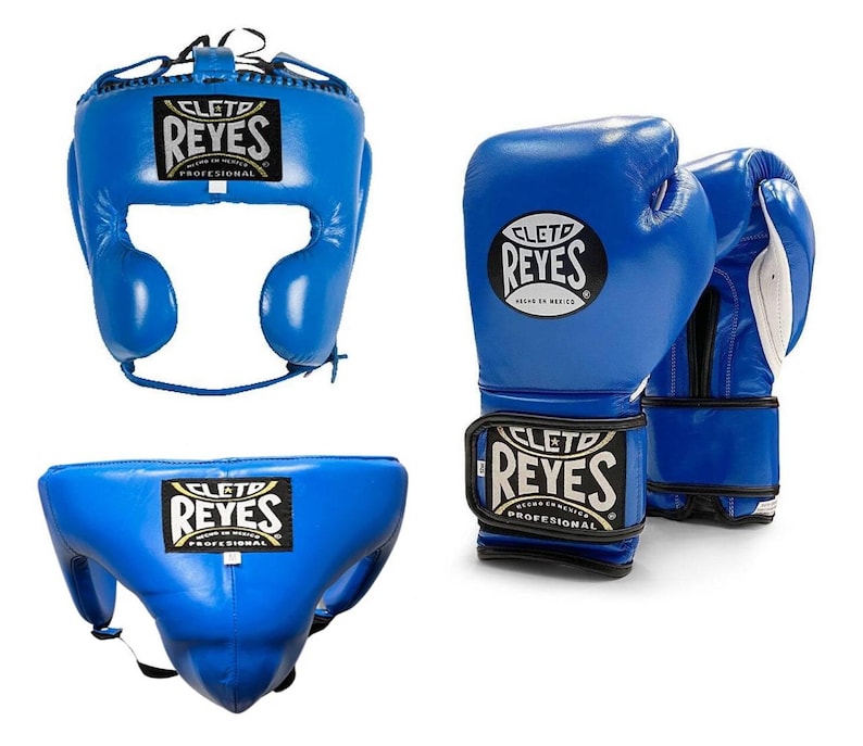 May include: A set of blue boxing equipment, including a head guard, a pair of gloves, and a groin protector. Each item features the "CLET0 REYES" logo in white and gold. The gloves have white accents on the inside.