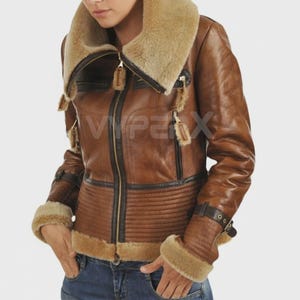 Puede incluir: Chaqueta de cuero marrón con cuello y puños de borrego. La chaqueta tiene cremallera, ribetes negros y un diseño acanalado en la parte inferior delantera. Los puños tienen cierres de hebilla. El texto "VIPERX" es visible.