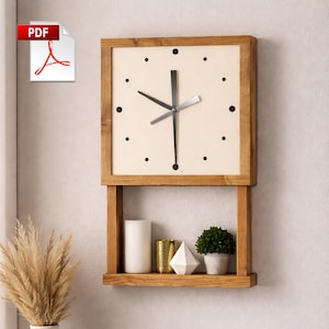 Puede incluir: Reloj de pared de madera con esfera cuadrada y estante debajo. La esfera del reloj es de color crema con puntos negros que marcan las horas. El estante contiene una vela blanca, un recipiente dorado, una forma geométrica blanca y una pequeña planta en maceta.