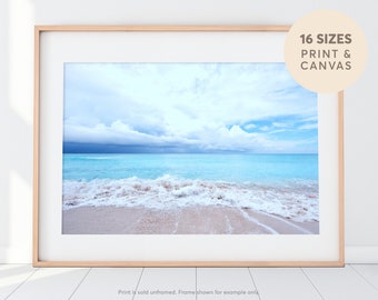 May include: A framed photograph of a beach scene with white foamy waves crashing on a sandy shore. The sky is a light blue with white clouds and a dark blue storm cloud in the distance.