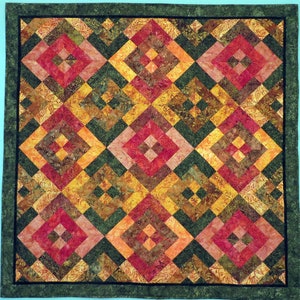 May include: A quilt with a geometric pattern of squares and diamonds in shades of red, orange, yellow, green, and brown. The quilt is framed with a dark green border.