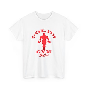 Könnte beinhalten: Ein weißes T-Shirt mit kurzen Ärmeln und einem roten Aufdruck auf der Brust. Das Motiv zeigt die Silhouette einer muskulösen Figur beim Gewichtheben mit dem Schriftzug Gold's Gym SoCal in roten Buchstaben darunter.