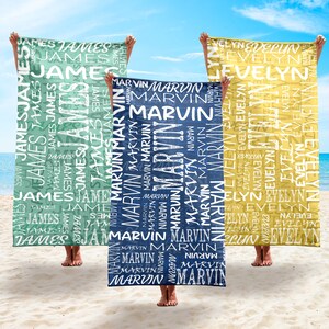 May include: Three personalized beach towels in shades of green, blue, and yellow are held up on a sandy beach. Each towel features a name in a repeating pattern. The names are James, Marvin, and Evelyn.