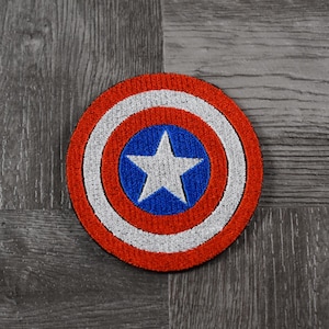 May include: A red, white, and blue embroidered patch with a white star in the center. The patch is circular and has a white border.