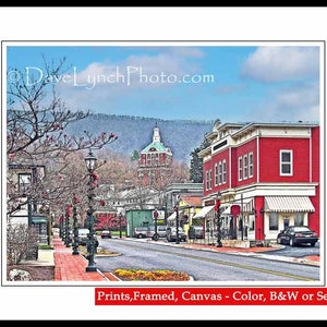 May include: A red brick building with a white awning and a sign that reads "Dave Lynch Photo.com". The building is located on a street with trees and other buildings in the background.