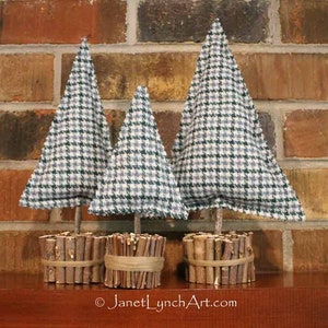 Può includere: Tre piccoli alberi di Natale in tessuto con un motivo a quadri in tonalità di verde e bianco. Gli alberi sono decorati con ramoscelli marroni e spago.