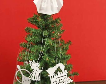 Pode incluir: Um enfeite de anjo de papel branco pendurado no topo de uma árvore de Natal verde. A árvore está decorada com outros enfeites de papel branco, incluindo um trem, um pássaro e dois anjos.