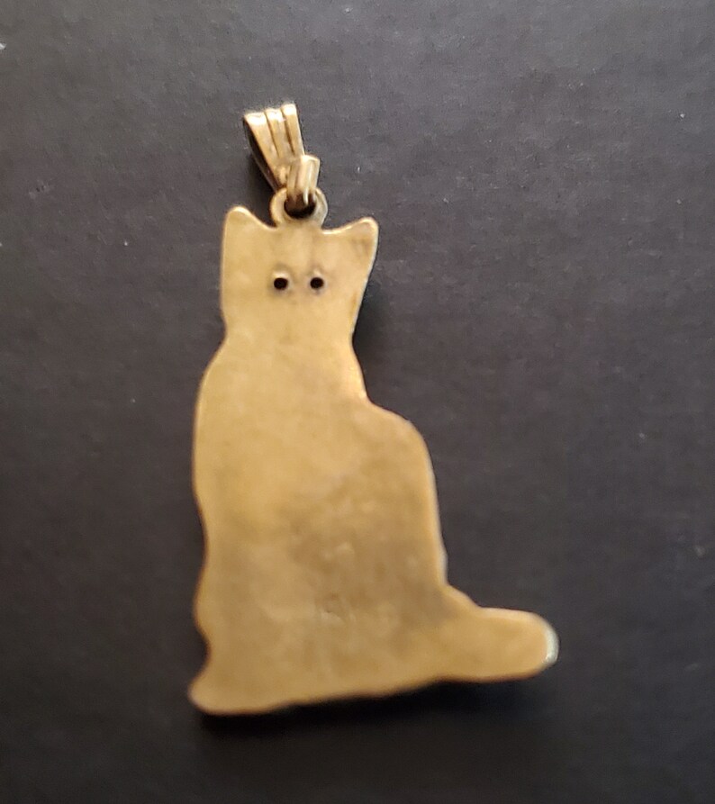 May include: Gold-toned metal pendant shaped like a sitting cat. The pendant has a loop at the top for attaching to a chain.