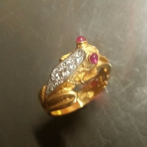 May include: A gold frog ring with two red gemstones and a row of clear gemstones on the back.