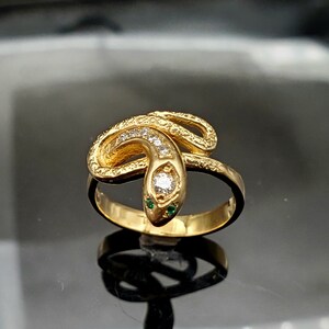 May include: A gold snake ring with a diamond and green stones for eyes.