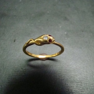 May include: A gold snake ring with red and white gemstones. The snake is coiled and has a detailed design.