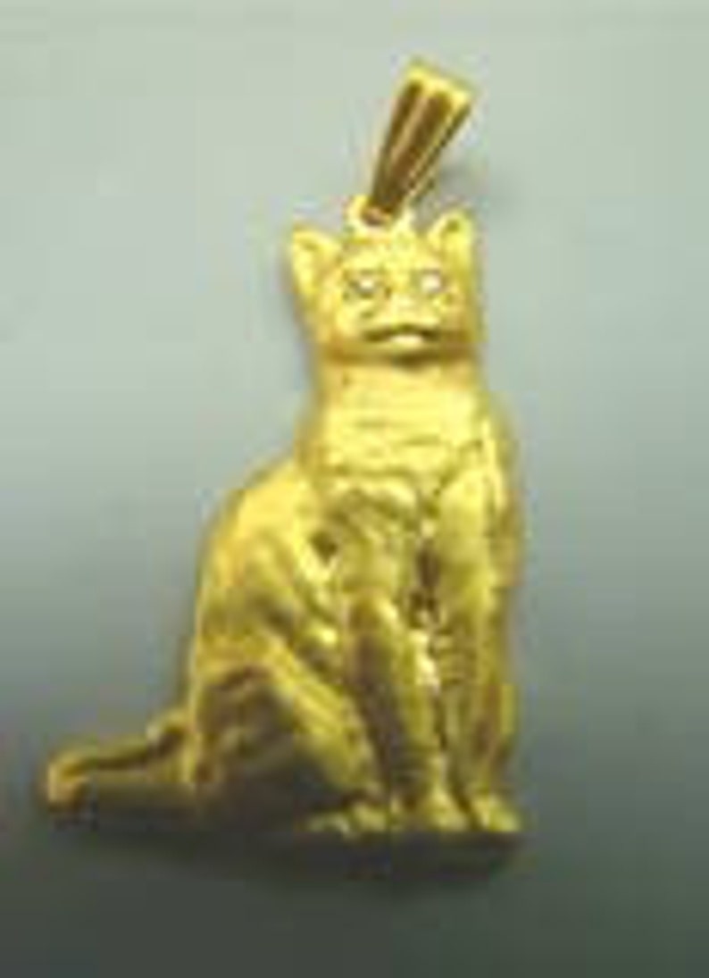 May include: A gold-colored cat pendant with a single clear gemstone for an eye.