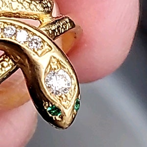 May include: A gold snake ring with a diamond and green stones for eyes.