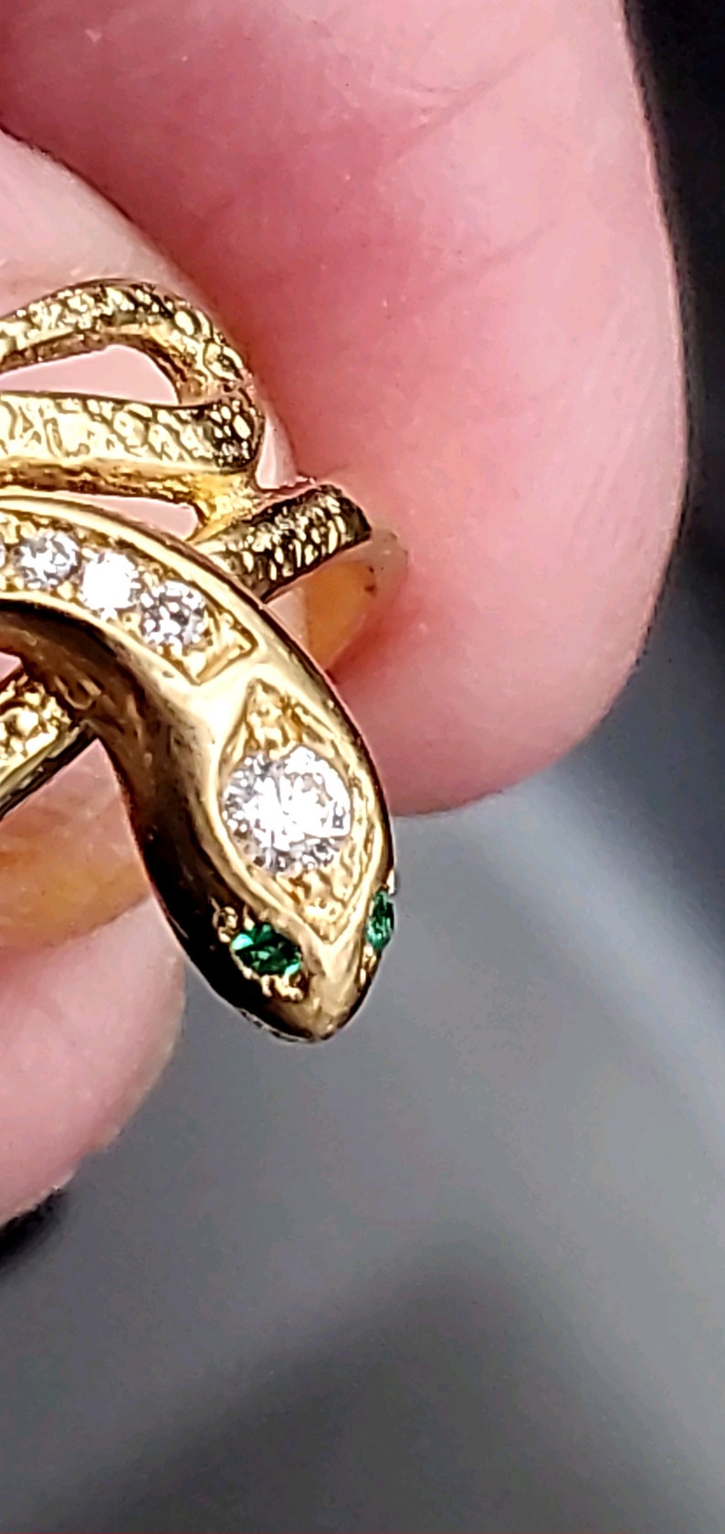 May include: A gold snake ring with a diamond and green stones for eyes.