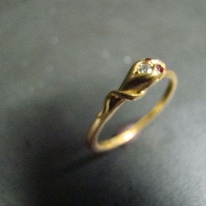 May include: A gold ring with a twisted band and a single red and white stone set in the top.