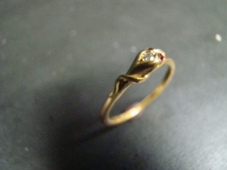 May include: A gold ring with a twisted band and a single red and white stone set in the top.