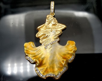 May include: A gold pendant featuring a detailed design of a woman with flowing hair and a flowing dress. The pendant is adorned with small diamonds around the edges.
