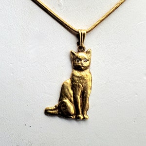 May include: A gold chain necklace with a gold cat pendant. The cat has diamond eyes.