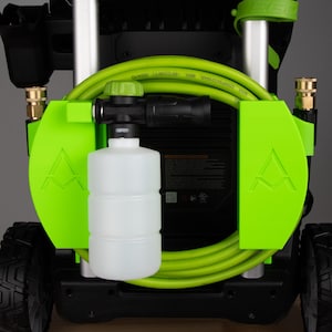 May include: A black and green pressure washer with a bright green hose and accents. The pressure washer has a white soap dispenser and two black wheels. The handle is black and the hose is coiled around the machine.