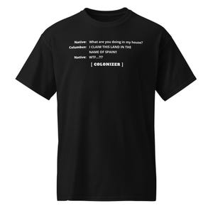 Könnte beinhalten: Schwarzes T-Shirt mit weißem Text. Der Text enthält einen Dialog zwischen "Native" und "Columbus" mit dem Satz "I CLAIM THIS LAND IN THE NAME OF SPAIN!!" und dem Wort "COLONIZER".