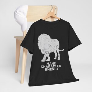 Puede incluir: Camiseta negra con una silueta blanca de un león y el texto "Mane Character Energy".