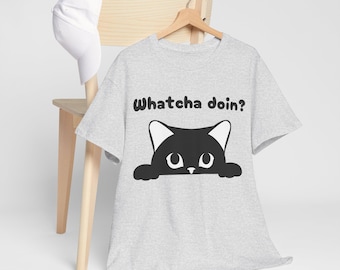 May include: A grey t-shirt featuring a black cat peeking out from behind a white surface. The cat has white ears and a black nose. The text "Whatcha doin?" is printed above the cat.