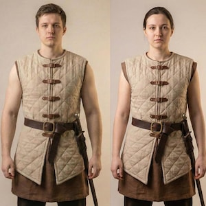 Könnte beinhalten: Eine beige gesteppte Weste mit braunen Lederriemen und passendem Gürtel. Die Weste hat ein Rautenmuster und wird mit einer braunen Tunika kombiniert. Ein Schwert ist am Gürtel befestigt.