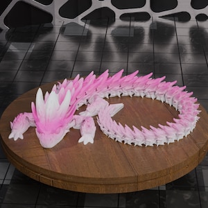 May include: A pink and white dragon sculpture with a detailed, spiky design. The dragon is posed on a round, wooden table. The sculpture's body is a gradient of pink, with white accents on the head and claws.