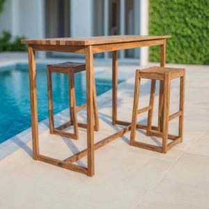 Peut inclure: Un ensemble de mobilier de bar extérieur en bois comprenant une table et deux tabourets. La table a un plateau rectangulaire et un design simple et moderne. Les tabourets sont carrés et ont un design similaire.