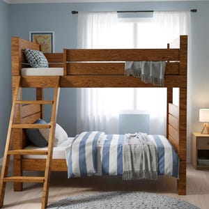 May include: A wooden bunk bed with a ladder, featuring a top bunk with a mattress and a bottom bunk with blue and white striped bedding. A gray blanket is draped over the top bunk. The room has light blue walls.