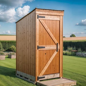 Puede incluir: Un cobertizo de almacenamiento exterior de madera con una sola puerta y una pequeña plataforma de madera. El cobertizo está construido con madera de color claro y presenta bisagras negras y un refuerzo diagonal en la puerta. El cobertizo está sobre un césped verde.