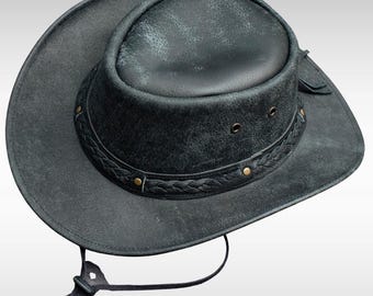 May include: A black leather cowboy hat with a wide brim and a braided band around the crown. The hat has a chin strap and is made of distressed leather. The hat is approximately 14 inches in diameter.