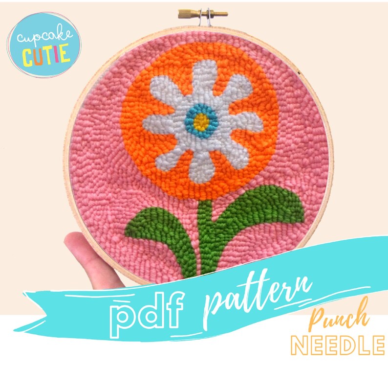 May include: A punch needle embroidery pattern featuring a large orange flower with a white center and green leaves on a pink background. The pattern is in a hoop and the text "pdf pattern Punch NEEDLE" is below the hoop.