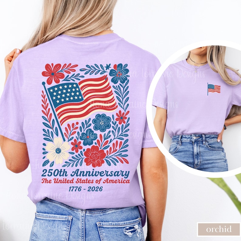 May include: A light purple t-shirt featuring a patriotic design. The back of the shirt displays an American flag with red and blue floral accents, and the text "250th Anniversary The United States of America 1776-2026". A smaller flag is on the front.