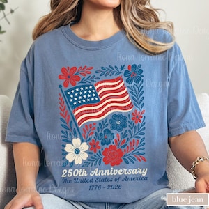 Puede incluir: Camiseta azul vaquero con un dise&ntilde;o patri&oacute;tico. El gr&aacute;fico incluye la bandera estadounidense, flores rojas y azules, y el texto "250th Anniversary The United States of America 1776-2026".
